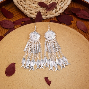 Detail view of silver bohemian tassel earrings with fish charms and sunburst studs