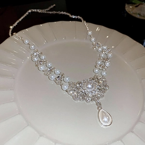 Detail of silver necklace featuring layered pearls and rhinestones with a teardrop pendant