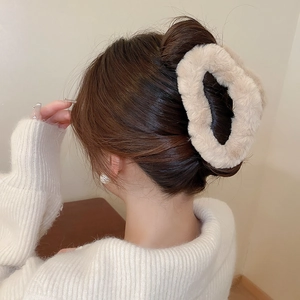 Detail of plush beige cross hair claw clip styled on back of head with a bun