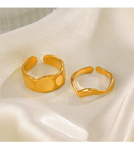 Detail of two gold plated stainless steel open rings on an elegant silk fabric backdrop