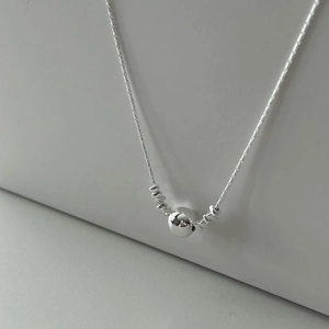 Close-up of a minimalist 925 sterling silver ball necklace with a polished mirror finish