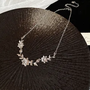 Elegant silver flower and leaf pendant necklace with zircon accents on a black textured tray