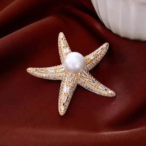 Macro shot of 14K gold plated starfish brooch with white pearl and sparkling crystals