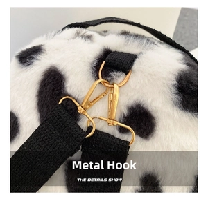 Detail of cow print plush backpack with gold metal hardware and black strap hooks