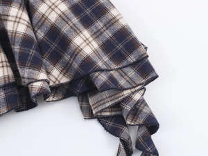 Close-up of layered plaid fabric with ruffled edges in navy and beige tones