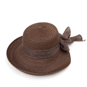Close-up of woven straw sun hat texture with elegant dark brown ribbon and large bow
