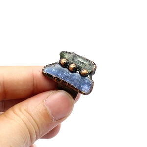 Handheld view of vintage copper ring featuring raw blue and green natural stones