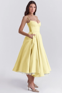 Detail of elegant yellow satin dress with thin shoulder straps and flowy double-layered skirt