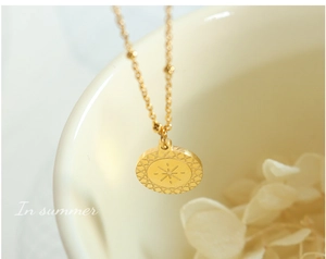 Dettaglio della collana con ciondolo a stella dorata e catena a sfere su fondo bianco