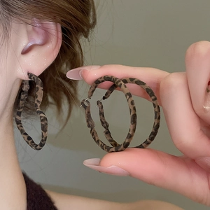 Gros plan de créoles imprimé léopard avec texture velours sur l'oreille d'un mannequin