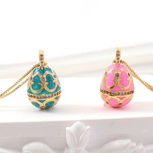 Detail of teal and pink enamel egg pendants with golden filigree and crystals