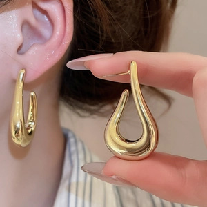 Macro detail of polished gold-finished water drop earrings with a metallic glossy surface