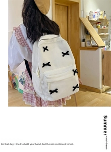 Close-up detail of white corduroy backpack showing black decorative X-shaped stitching