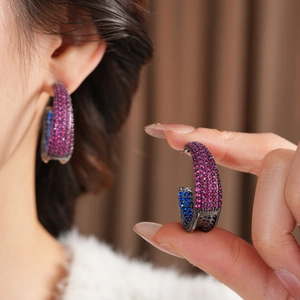 Macro shot of large C-shaped earrings with colorful pave zircon stones and metal base
