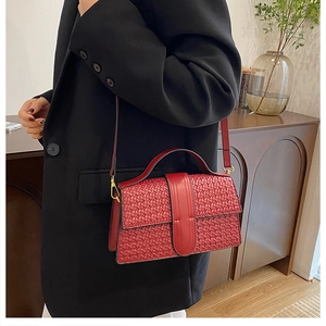 Detail of red woven texture shoulder bag with golden buckle and adjustable strap