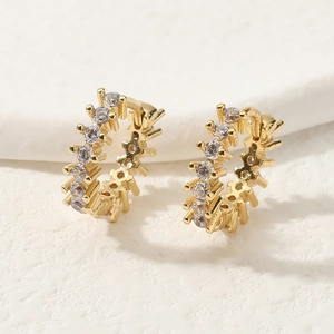 Macro de pendientes de aro dorados con micro pavé de circonitas sobre fondo blanco texturizado