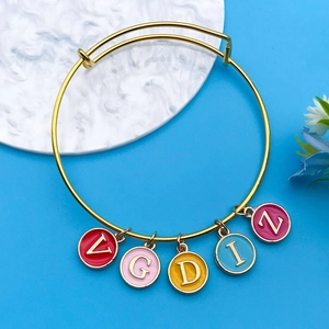Close-up of golden adjustable bracelet with five colorful enamel letter pendants