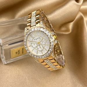 Detailed close-up of a luxury gold quartz watch with zircon-set bezel on silk fabric