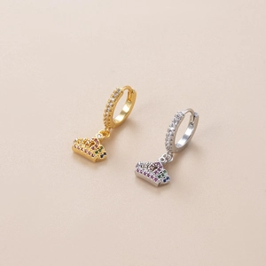 Close-up of gold and silver crown charms with colorful zircons on huggie hoop earrings
