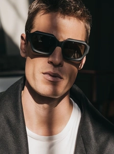 Close-up of geometric black hexagonal sunglasses on a model with artistic shadows