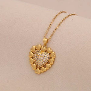 Detailed view of gold heart pendant with micro-pave cubic zirconia on beige fabric