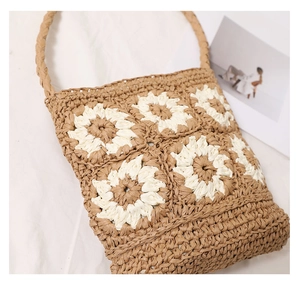 Detail of handmade crochet straw tote bag with daisy pattern and woven texture