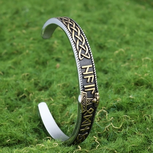 Detail of Viking Thor Hammer open cuff bracelet with runes on green moss background