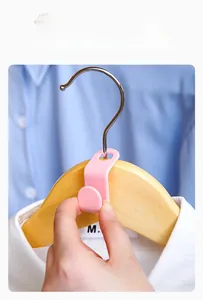Pink ABS plastic hanger connector hook being installed on a wooden hanger for storage