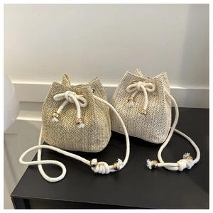Detail of woven straw bucket bags showing khaki and cream fabric texture and metal beads