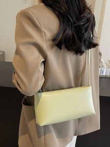 Elegant light green rectangle leather underarm bag worn with a stylish beige blazer coat