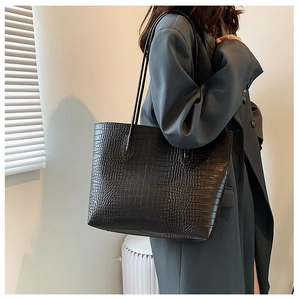 Detailed view of black crocodile pattern leather tote bag on model for urban style