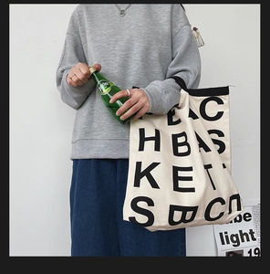 Lifestyle shot of large cream canvas tote bag with black letter print and web handles