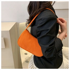 Chic orange corduroy baguette bag worn by a model in a black blazer and white skirt