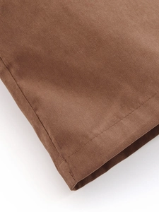 Detailed close-up showing stitching and texture on brown fabric of a blazer and shorts