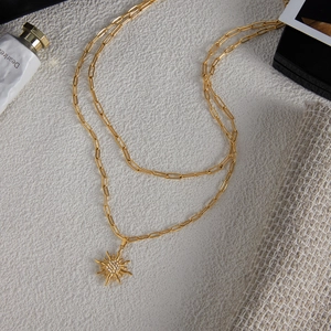 Dettaglio di una collana a doppio strato dorata con ciondolo a sole e strass brillanti