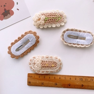 Set of four 7cm handmade knitted flower hair clips with wood ruler for size reference