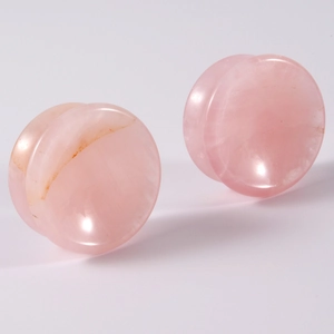 Macro shot of natural pink quartz double flared ear plugs with smooth stone texture