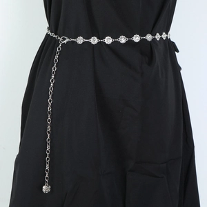 Close-up of silver metal waist chain with flower links on a black dress