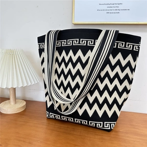 Close-up of knitted tote bag with chevron pattern on a minimalist wooden table