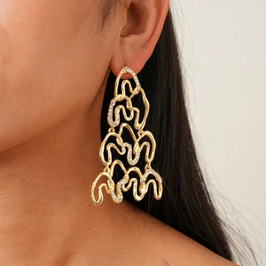 Macro detail of large gold geometric twist earrings with sparkling inlaid rhinestones