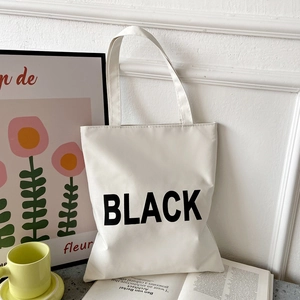 Minimalist white oxford tote bag with black print shown in a stylish room setting