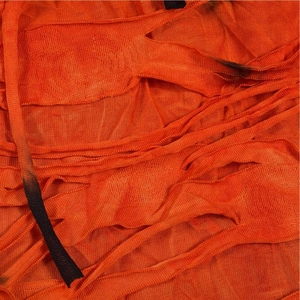 Detailed macro view of orange mesh fabric with distressed fringe and ripped texture details