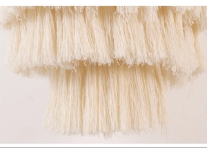 Close-up of ivory white hand-woven cotton lamp shade with multi-layered long fringe texture