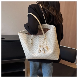 Detalle del bolso tote grande con monograma y costuras en las asas con colgante de perrito