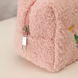 Close-up of pink plush makeup bag featuring soft fleece texture and silver zipper detail