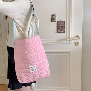 Pink quilted cotton tote bag with heart patterns and blue shoulder strap shown on model