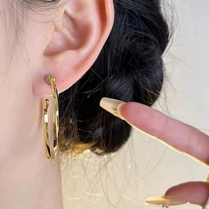 Close-up of model wearing a large polished golden hoop earring for minimalist style
