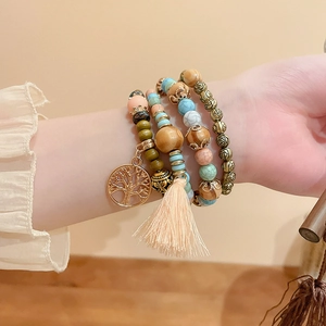 Detail of bohemian layered sandalwood bead bracelet with tree of life charm and peach tassel