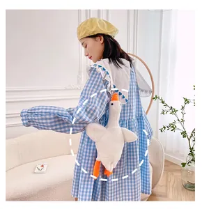 Plush white goose crossbody bag with orange accents shown on a female model