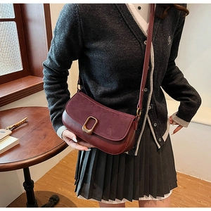 Detail of dark red crossbody bag with suede texture and golden rectangular lock buckle